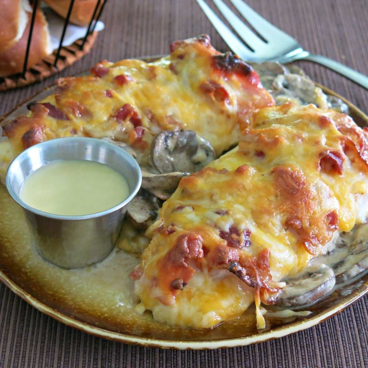 Copycat Alice Springs Chicken on a plate with a condiment cup with extra honey mustard sauce.