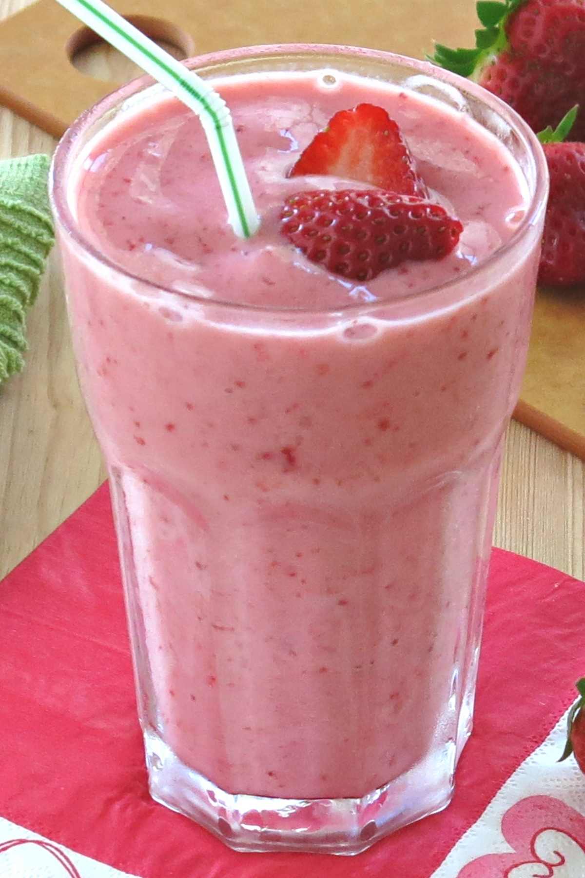 Easy strawberry smoothie with yogurt and ice in a tall glass with a straw.