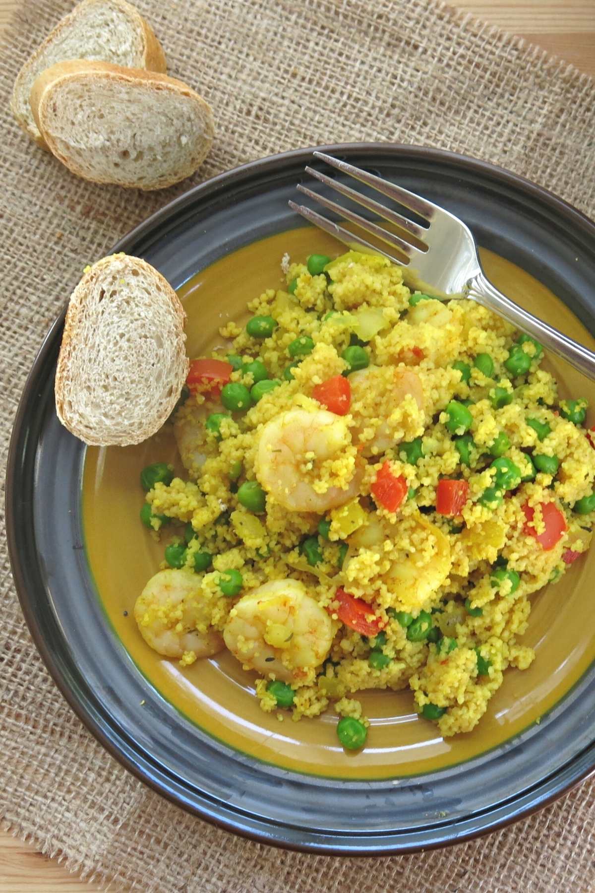 One pot shrimp couscous paella on a plate with bread.
