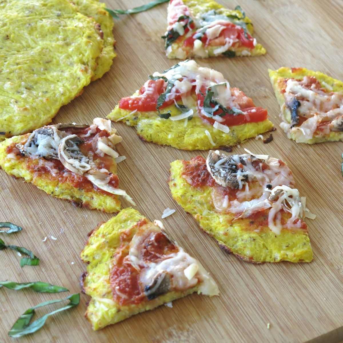 Slices of cooked spaghetti squash pizza on a cutting board.