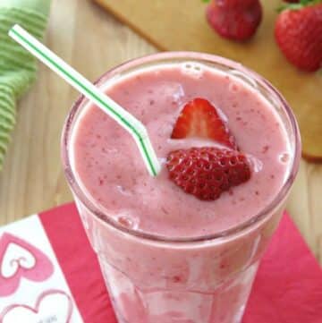 Simple strawberry smoothie with yogurt in a glass with strawberries on top.