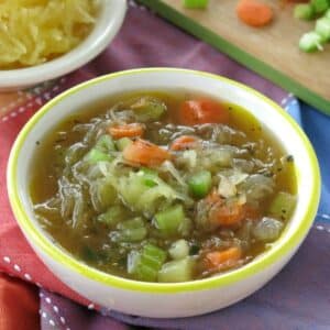 Easy spaghetti squash soup in a bowl with a bowl of spaghetti squash and cut vegetables behind it.