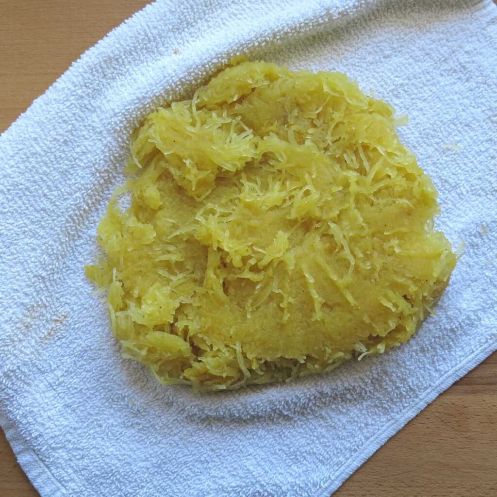 Spaghetti squash strands with liquid removed on a dish cloth.