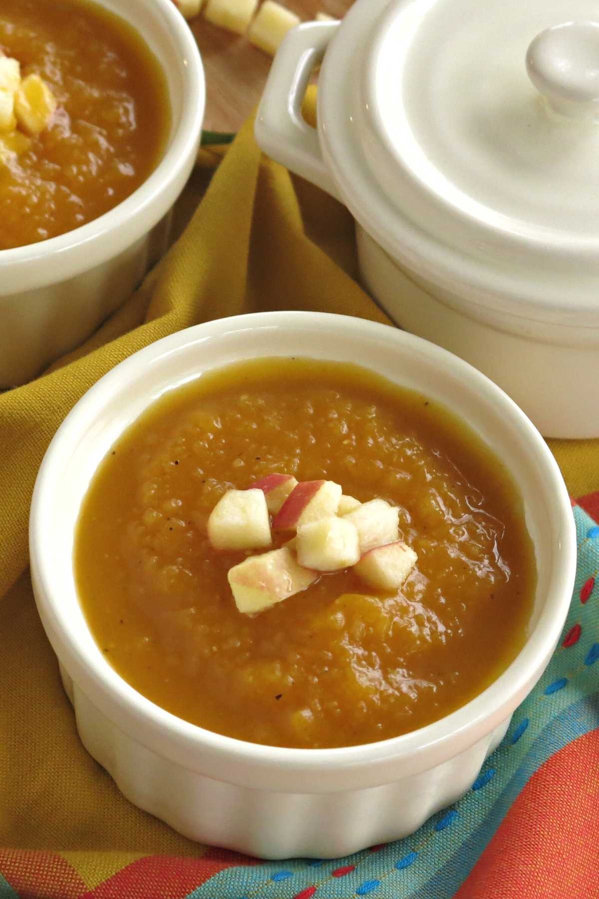 Sweet and Spicy butternut squash soup in a bowl with more cups behind it.