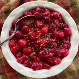 Low-sugar cranberry sauce garnished with orange zest in a bowl with a spoon.