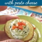 Fingers holding pesto cheese potato rounds appetizer.