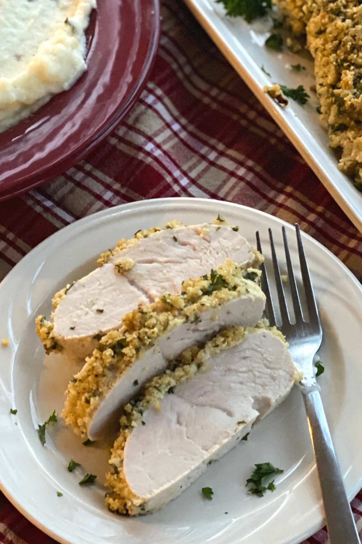 Three slices of herb crusted turkey tenderloins on a polate.