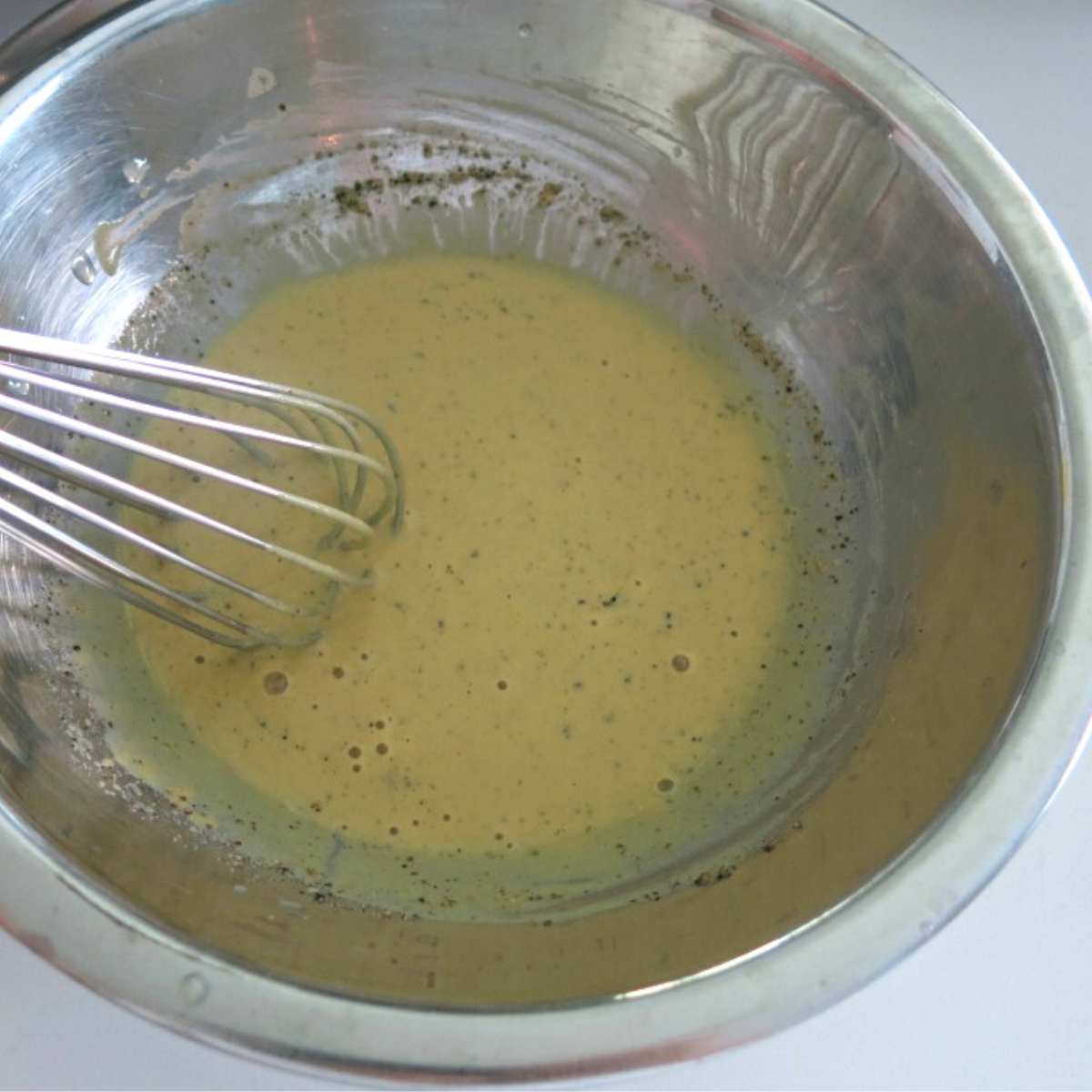 Dijon mustard, lemon sauce in a bowl with a whisk.