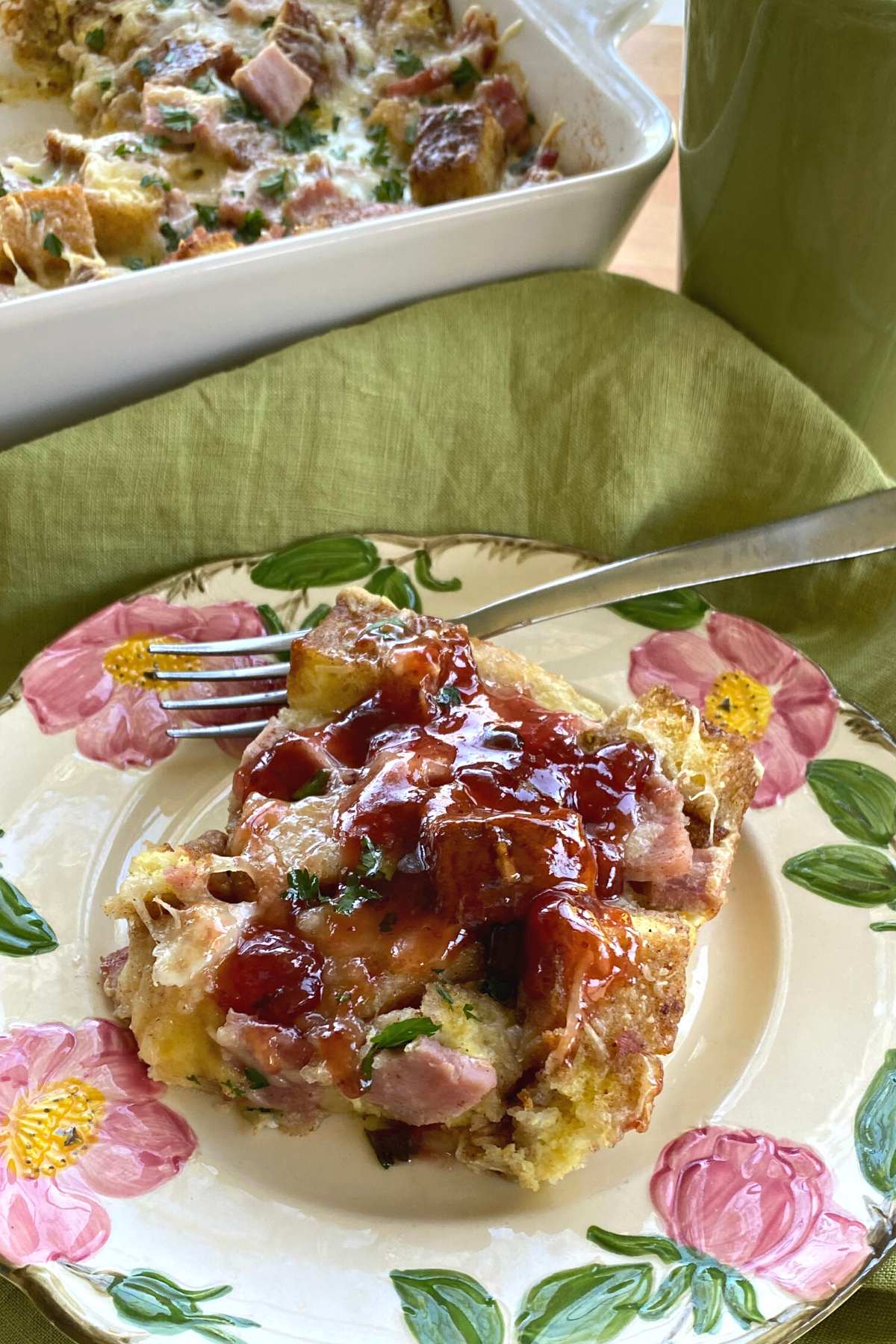 Monte cristo casserole with french toast on a plate with casserole dish behind it.