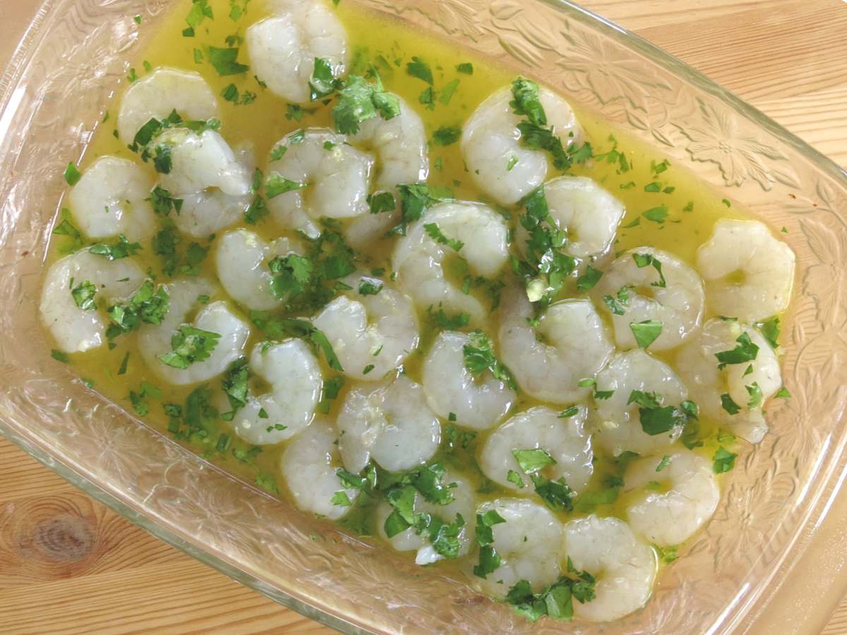 Medium-sized shrimp marinating in a margarita shrimp marinade in a glass dish. 