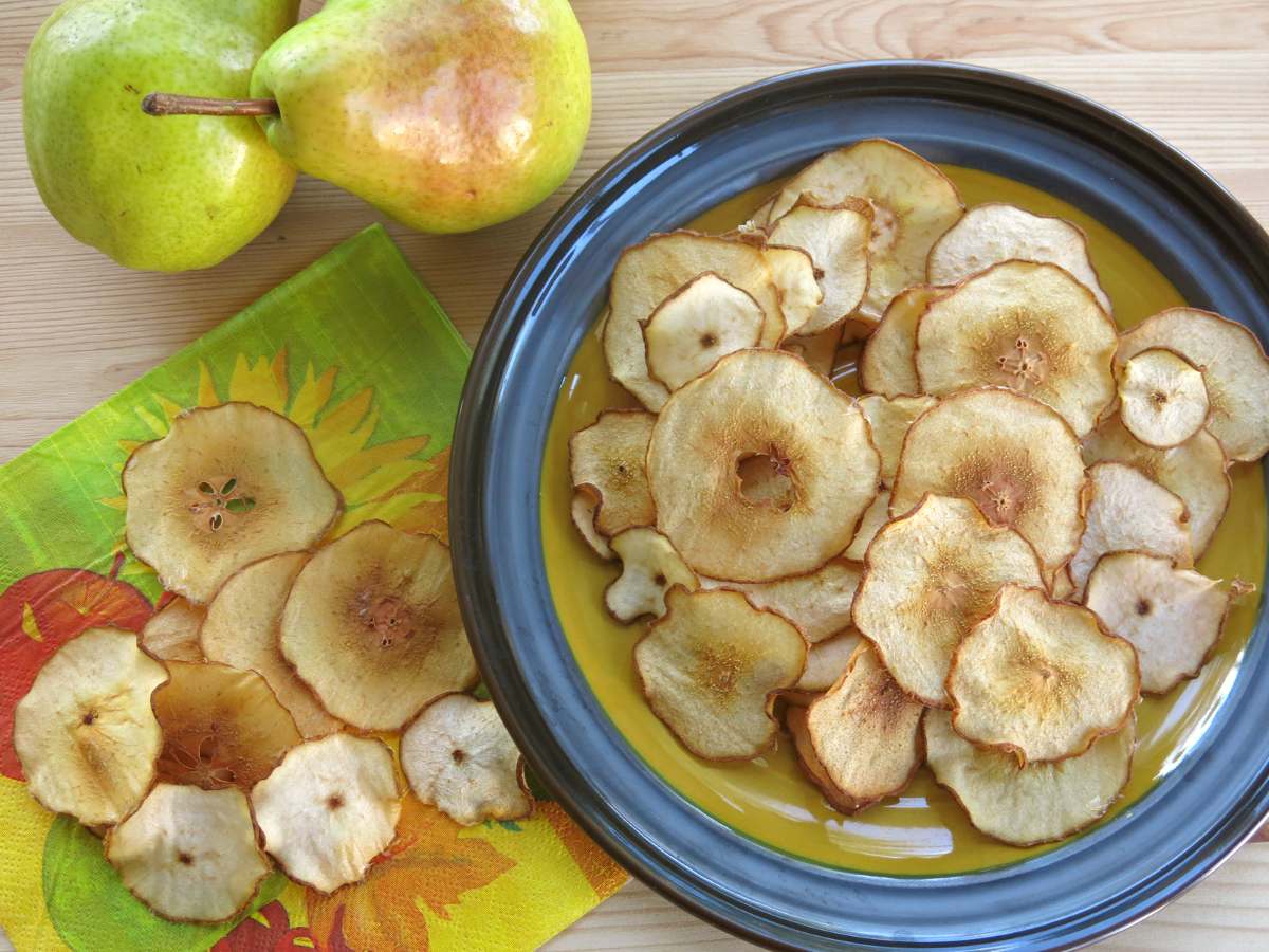 Pear chips on a plate and napkin with 2 pears next to it.