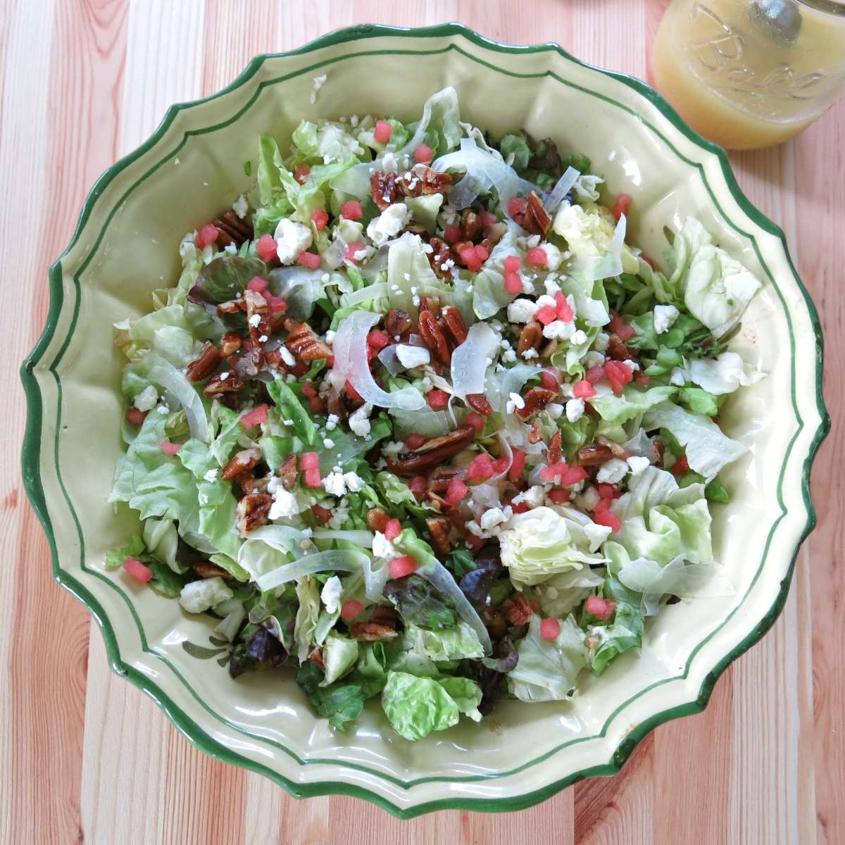 Summer fennel salad with shaved fennel, feta cheese, candied pecans, and watermelon in a large bowl.