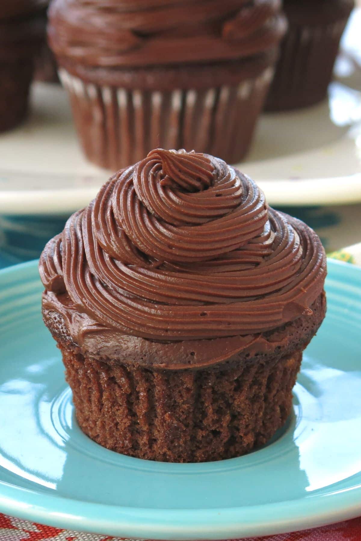 Wacky chocolate cupcake made with out egg on a plate with more cupcakes behind it.