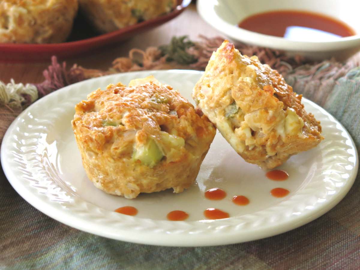Two buffalo chicken meatloaf muffins on a white plate with drops of buffalo sauce on the plate.