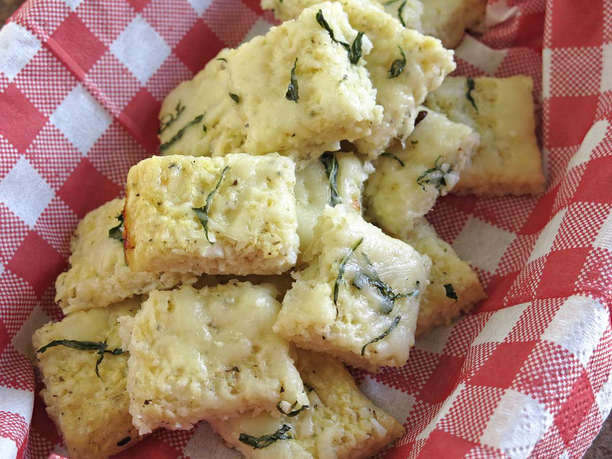 Low-carb cauliflower pizza bites in a basket with a red checkered napkin.