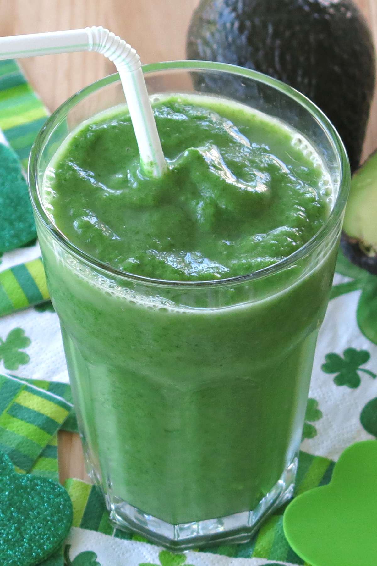 Pineapple green smoothie with avocado in a glass with a straw.