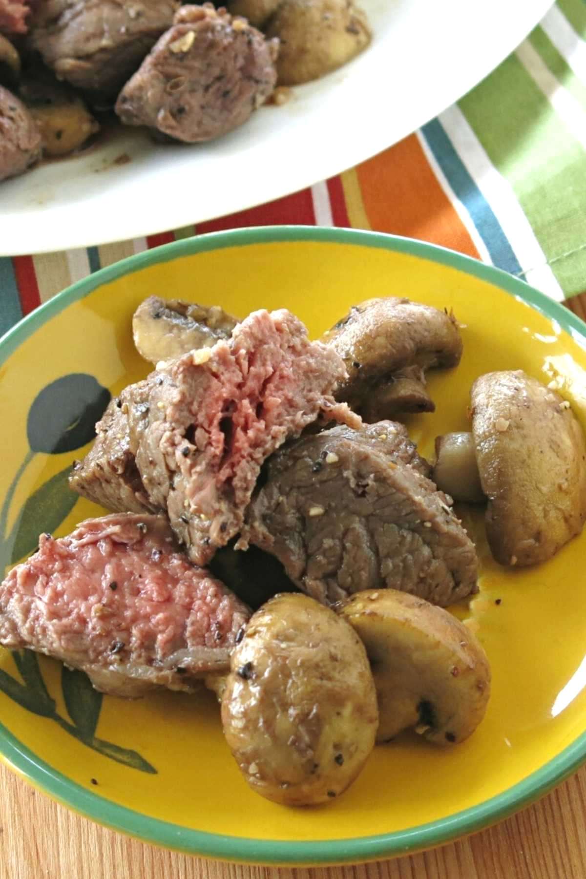 Steak bites and mushrooms made in an air fryer on a plate.