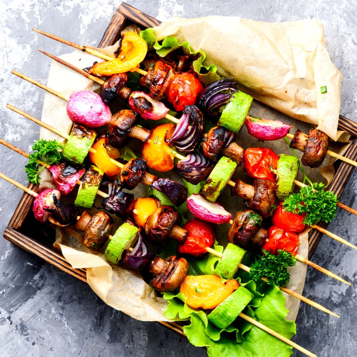 Six skewers with grilled vegetables with tomatoes, zucchini, radishes, mushrooms, and peppers.