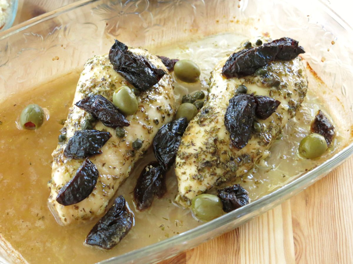 Baked Chicken Marbella with prunes and olives in a baking dish.