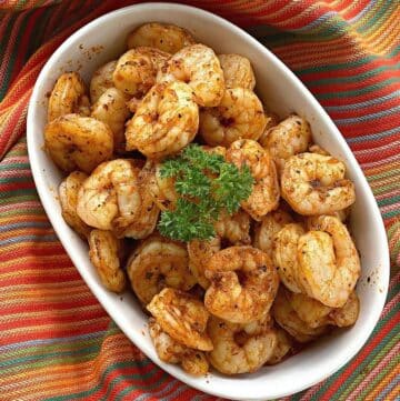 Easy blackened shrimp in a bowl with a sprig of parsley on top.