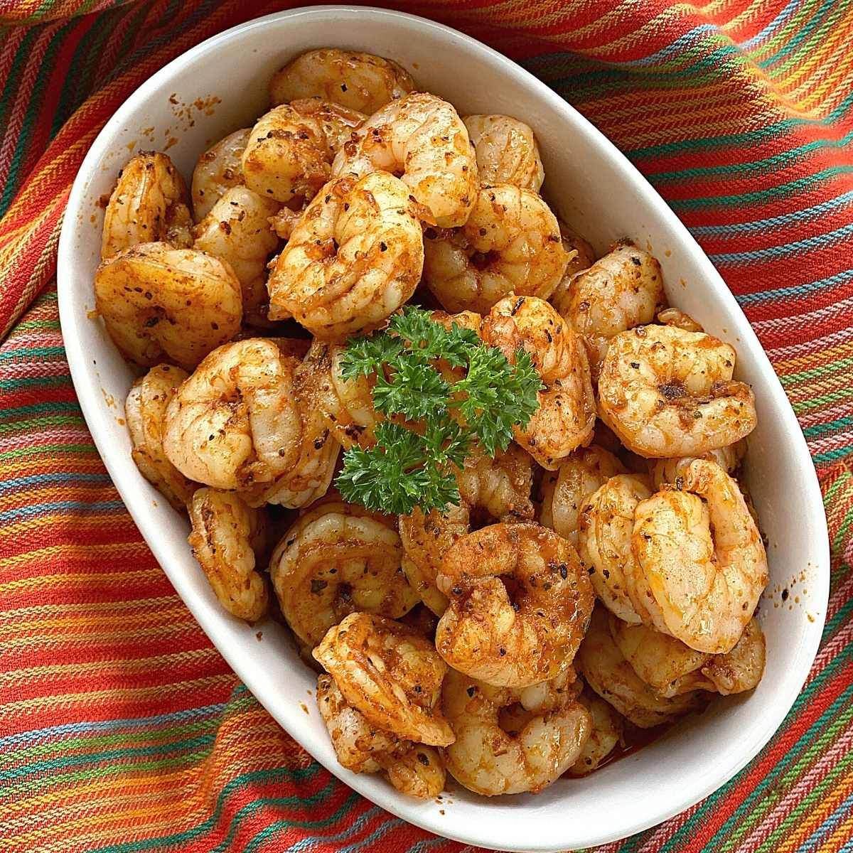 Easy blackened shrimp in a bowl with a sprig of parsley on top.
