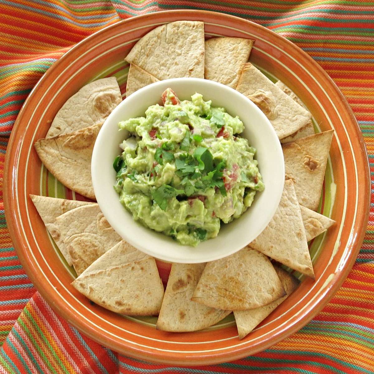 Keto tortilla chips surrounding a bowl of guacamole.