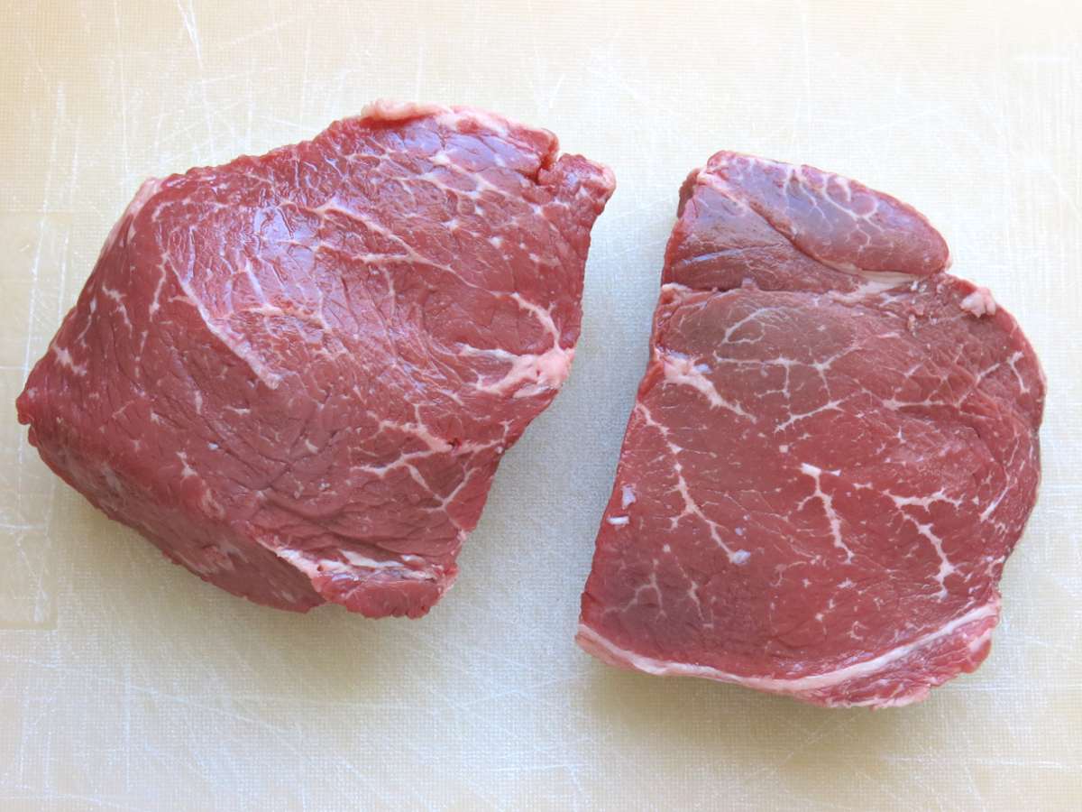 Two sirloin steak filets on a cutting board.