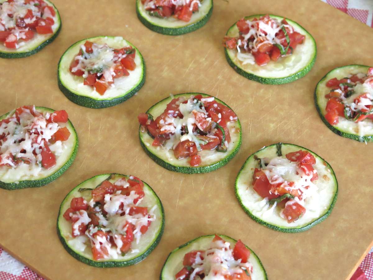 Board with lines of zucchini bruschetta on it.
