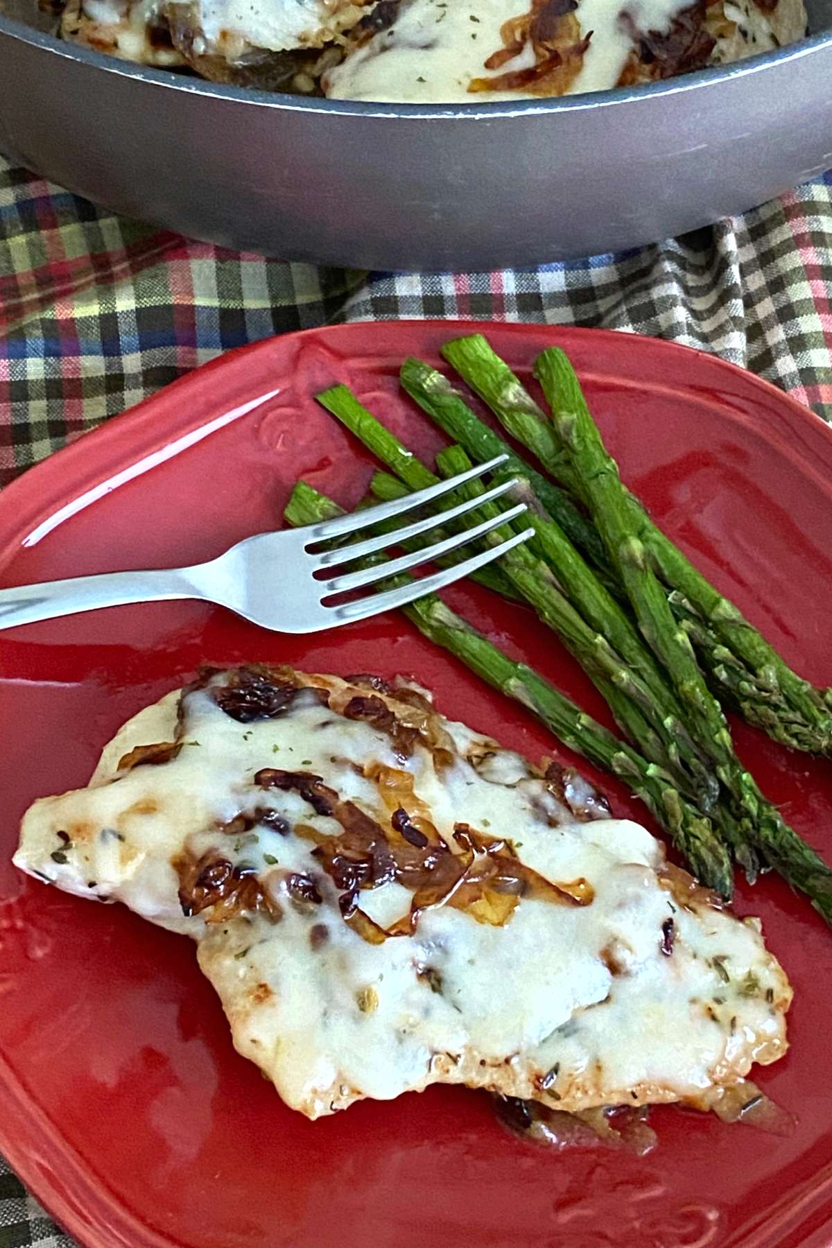 French onion chicken on a plate with asparagus.