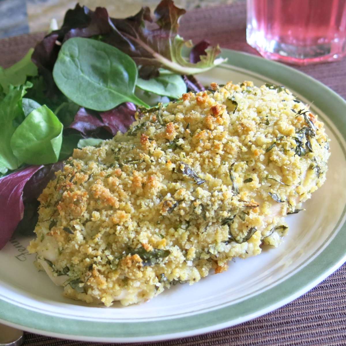 Parmesan Herb Crusted Chicken on a plate next to salad greens.