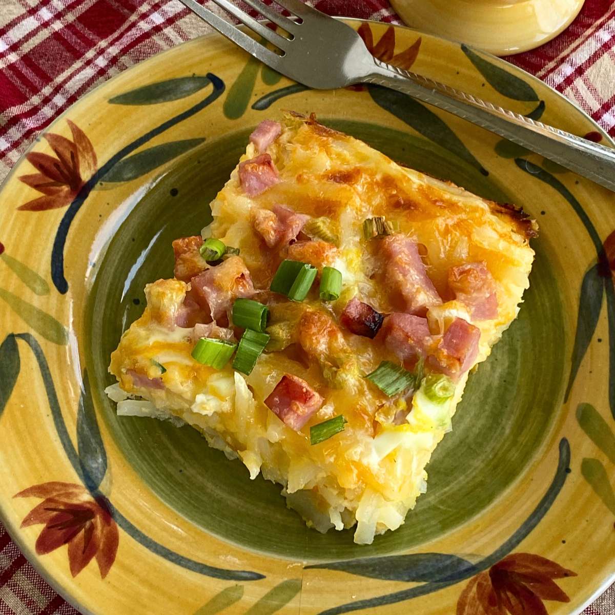 Serving of hash brown breakfast casserole made with Simply potatoes on a plate with a fork.