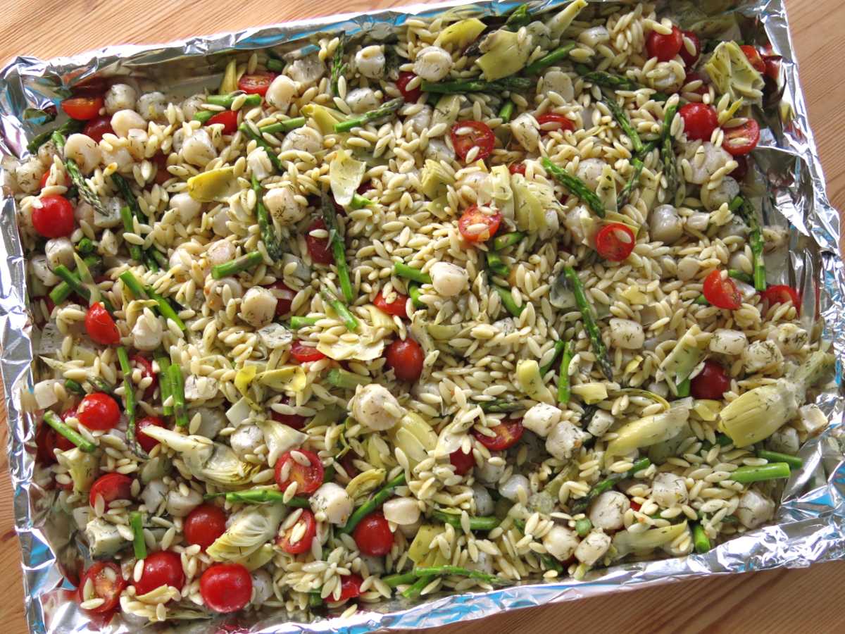 Warm orzo salad ingredients on a sheet pan.