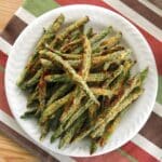 Keto-friendly, baked green bean fries coated in Parmesan cheese on a plate.