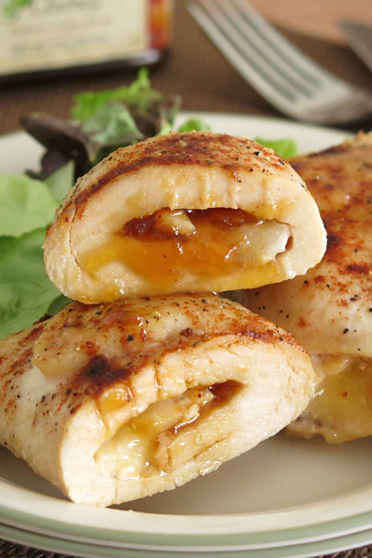 Chicken roulades stacked on a plate with mango chutney and brie oozing out.