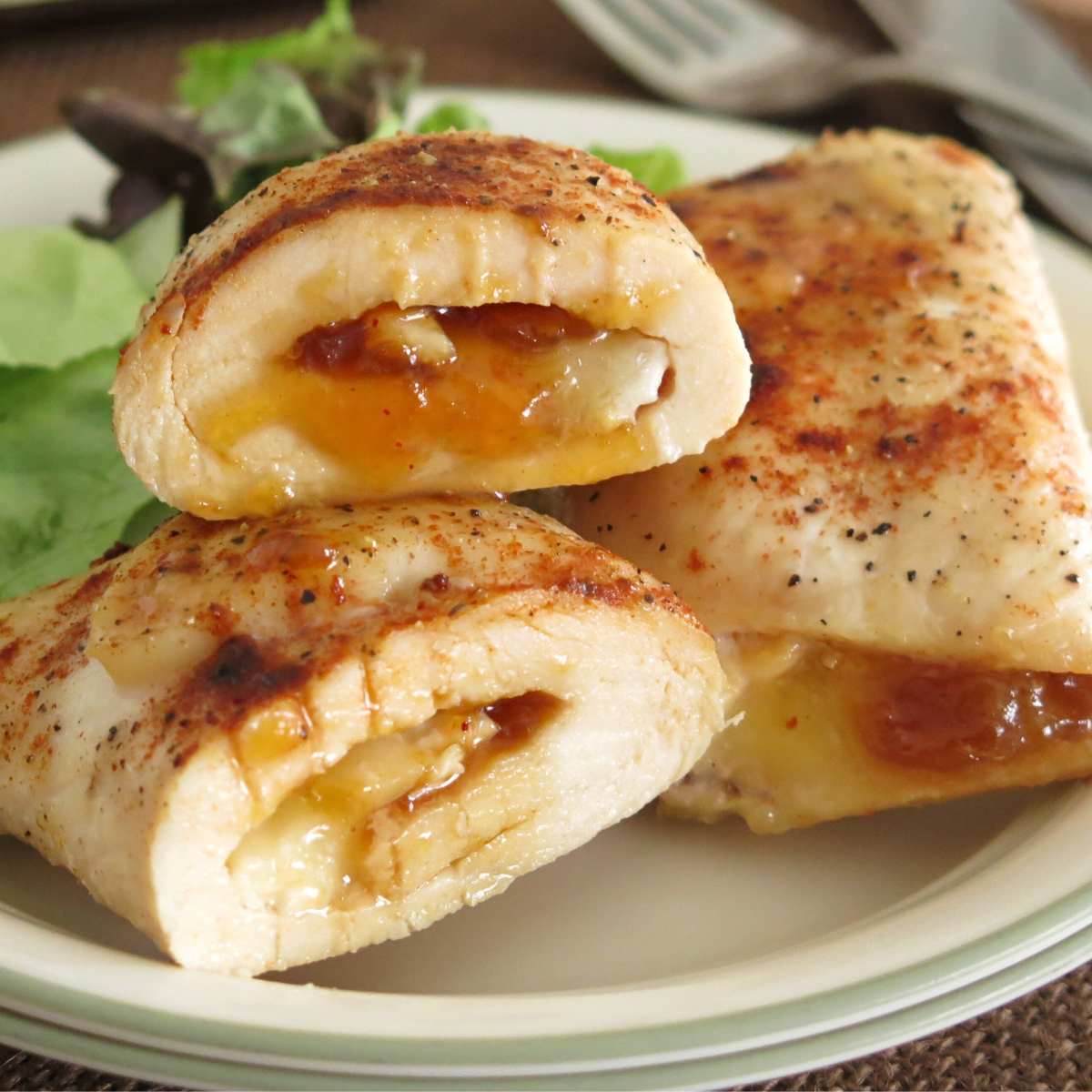 Chicken roulades filled with mango chutney and brie on a plate.