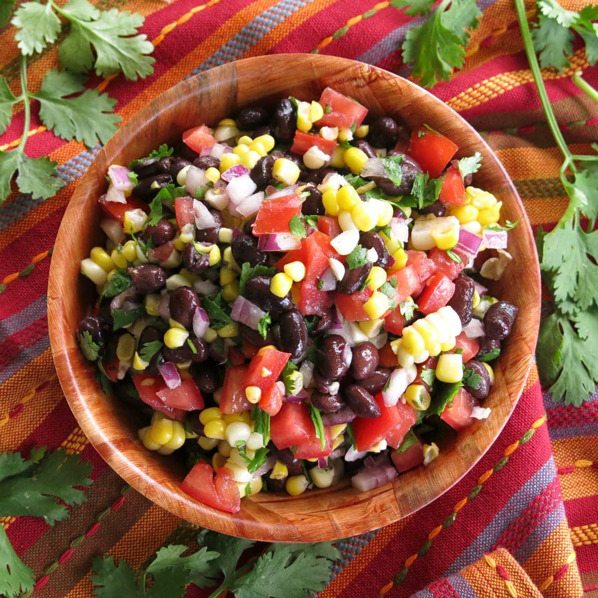 Fresh corn and black bean salsa with red wine vinegar dressing in a wooden bowl.