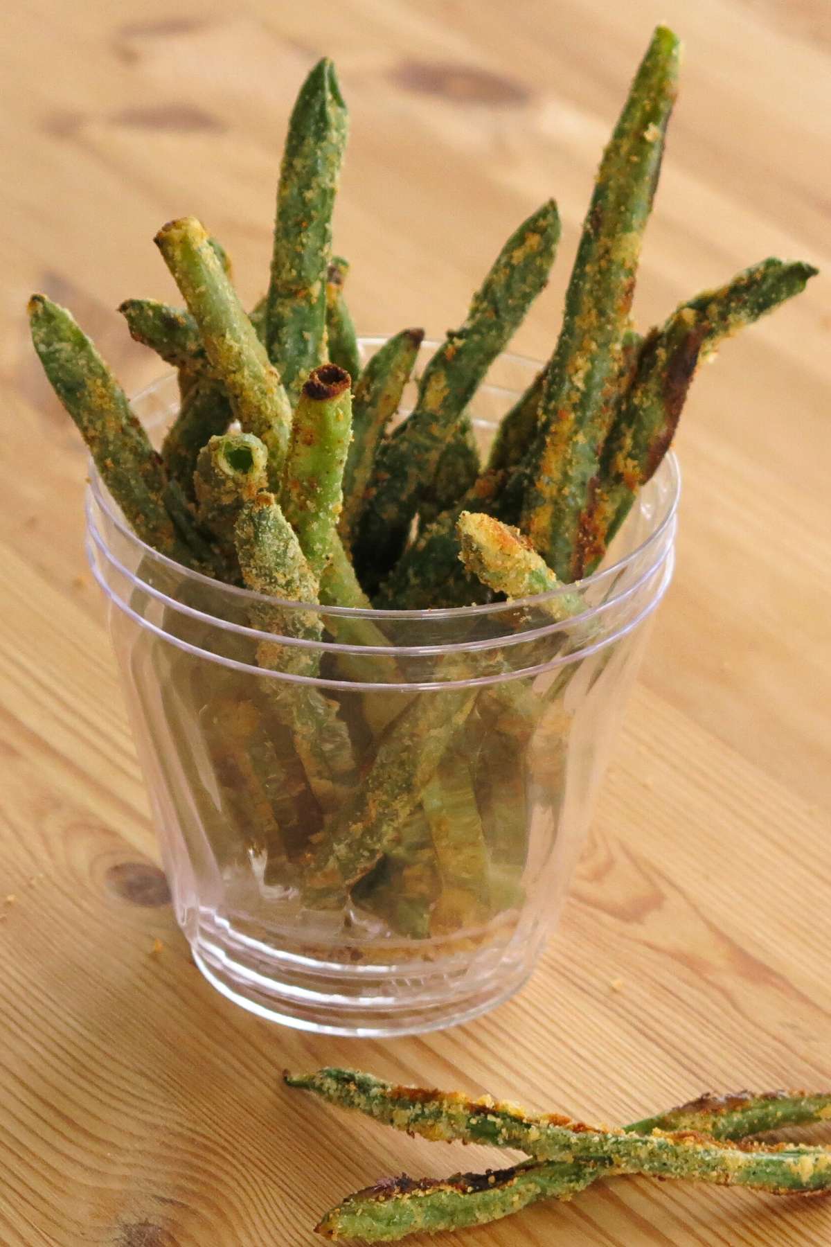 Keto green bean fries standing in a clear cup.