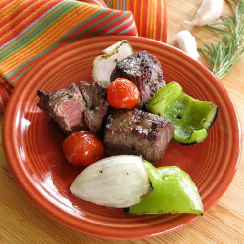 Plate with red wine marinated steak shish kabobs removed from skewers.