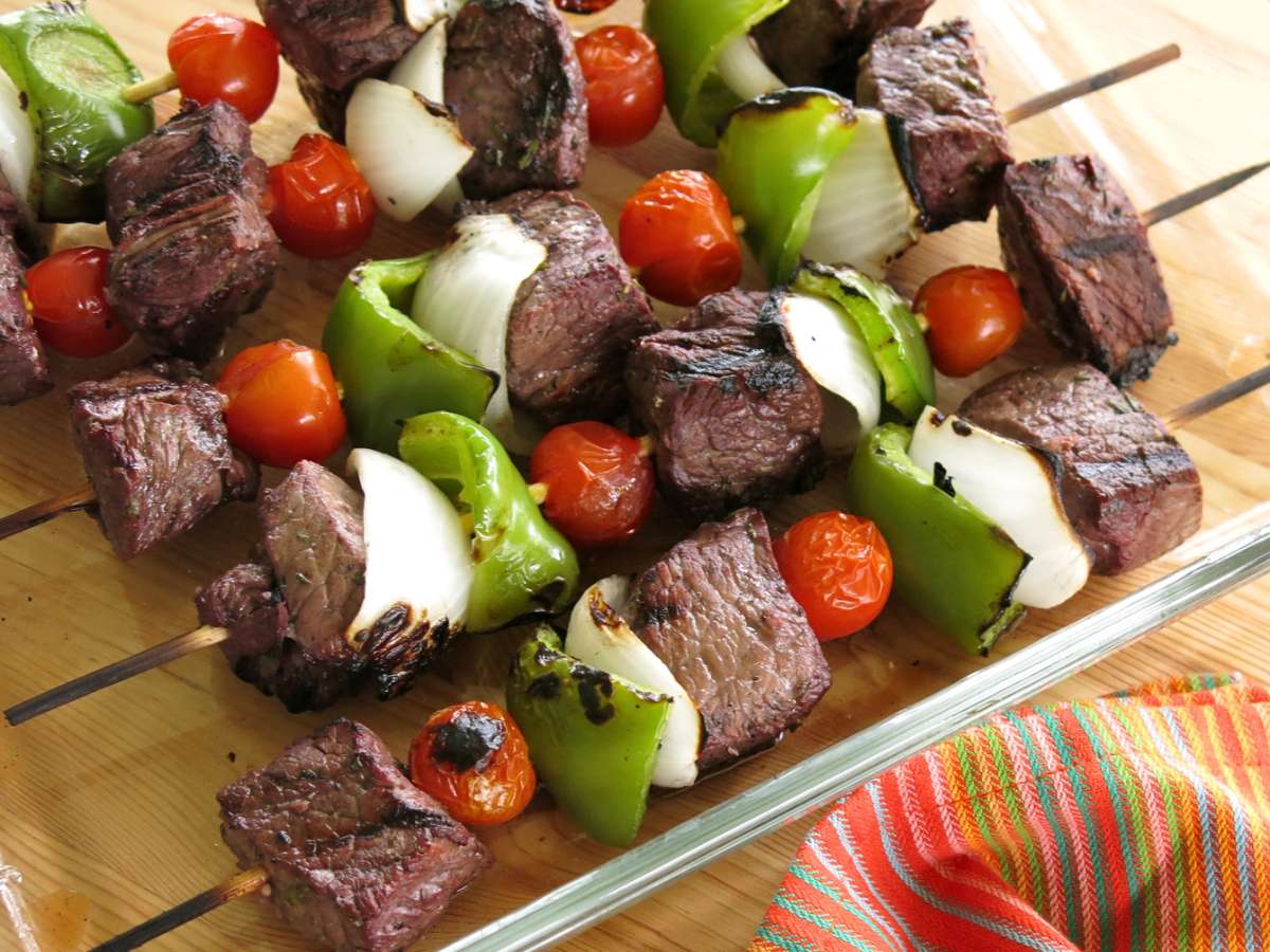 Grilled red wine marinated steak kabobs in a glass dish.