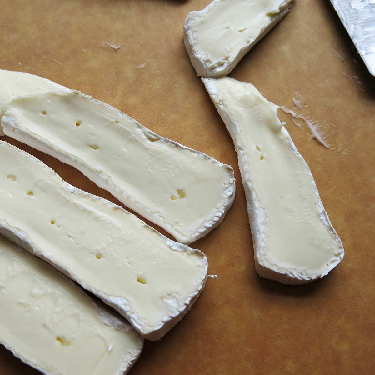 Slices of brie cheese on a cutting board.