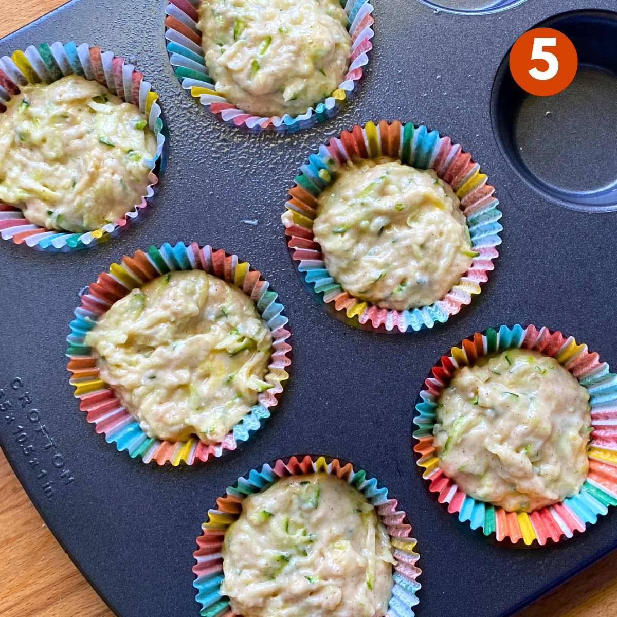 Uncooked zucchini muffins in a muffin pan.