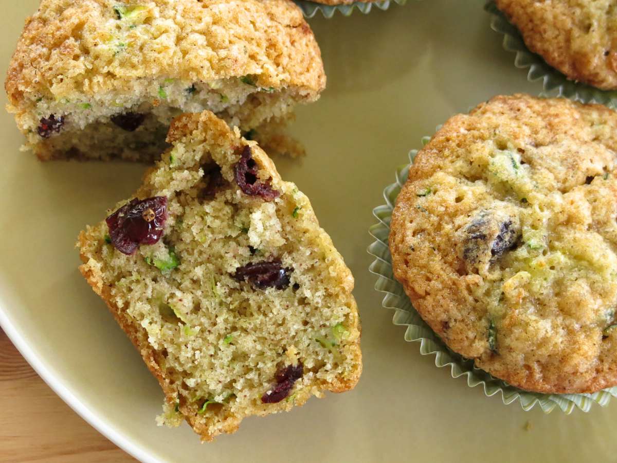 A zucchini yogurt muffin cut in half next to a whole muffin.