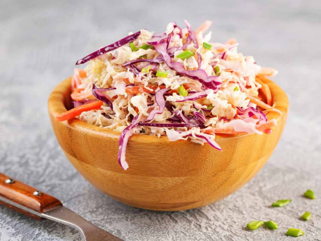 Coleslaw with red cabbage and carrots in a wooden bowl.