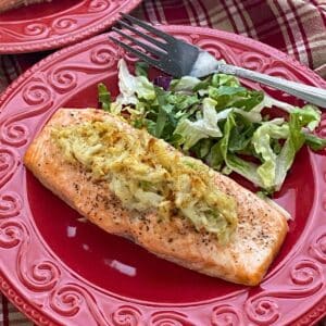 Crab stuffed salmon on a red plate with a salad and fork next to it.