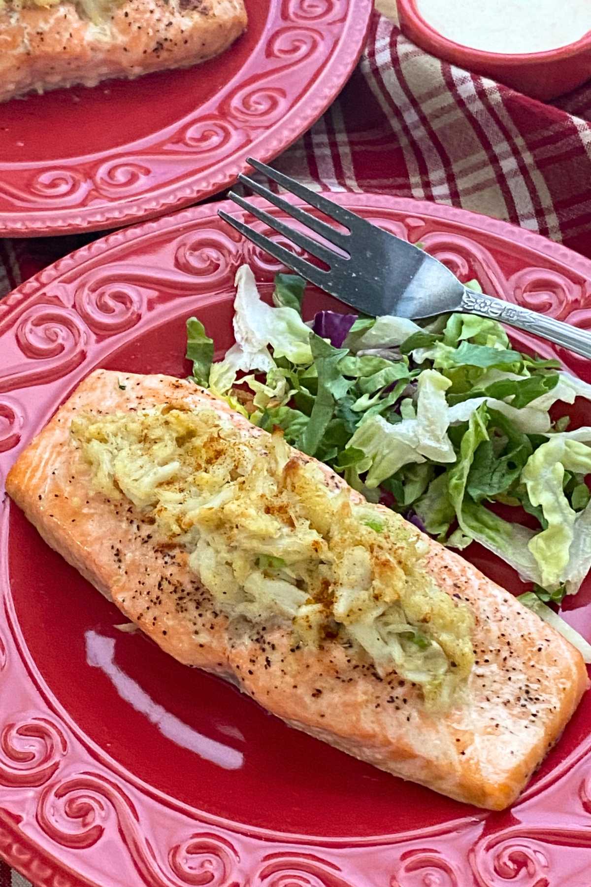 Crab stuffed salmon on a plate with another plate behind it with another serving.