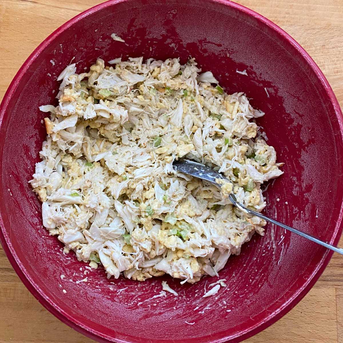 Crab stuffing in a red bowl with a spoon.