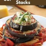 Eggplant parmesan stack on a plate on top of pasta.