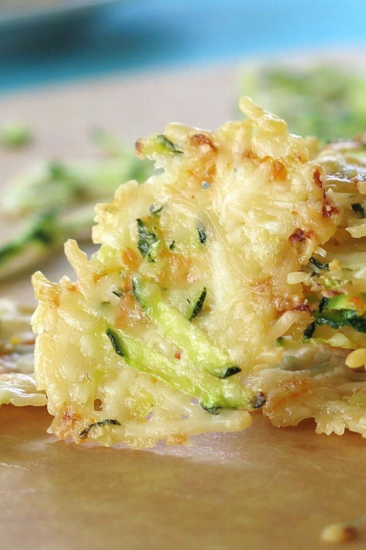 Parmesan cheese veggie crisp standing on end next to a stack of more parmesan crisps.