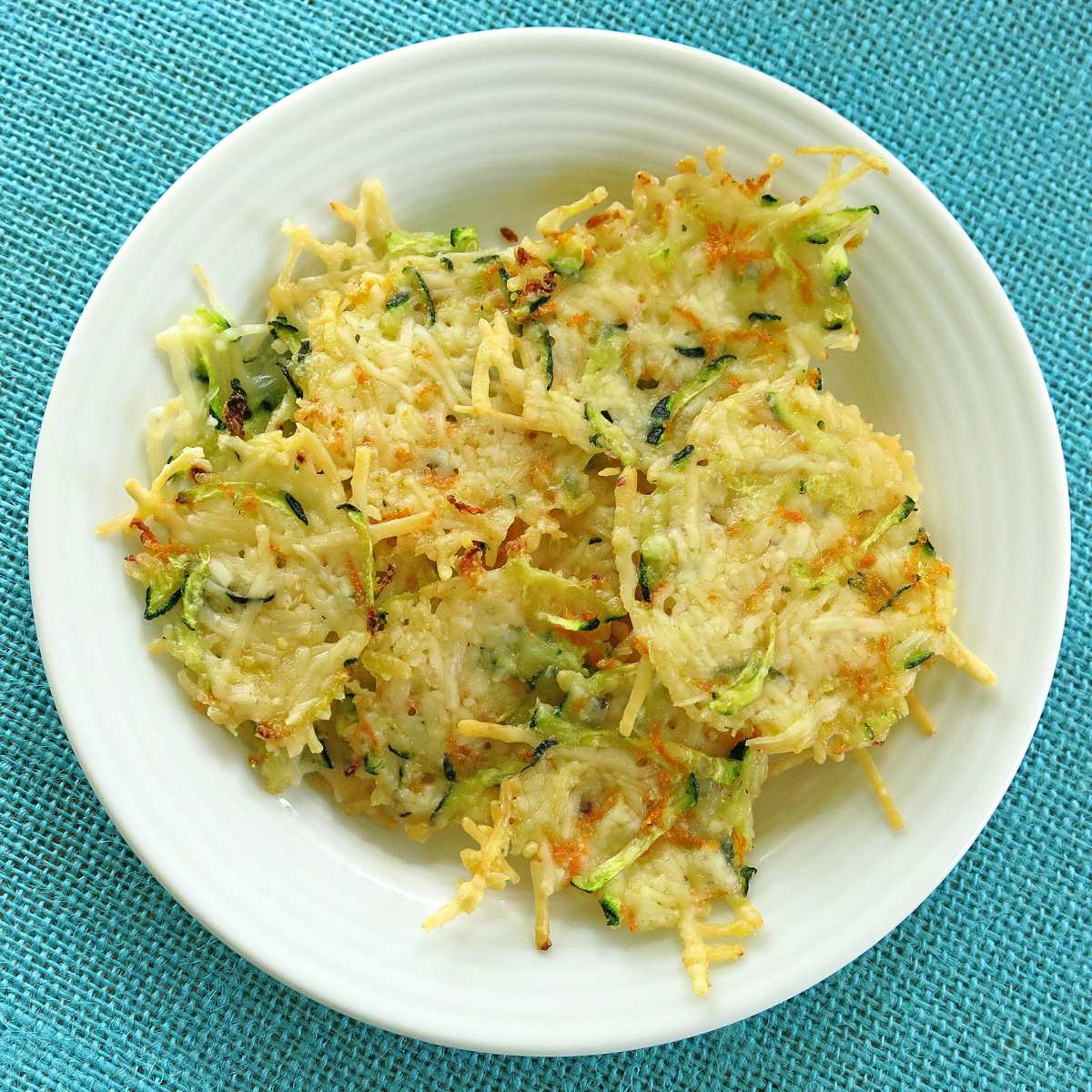 Overhead shot of parmsan zucchini and carrot chips on a white plate.