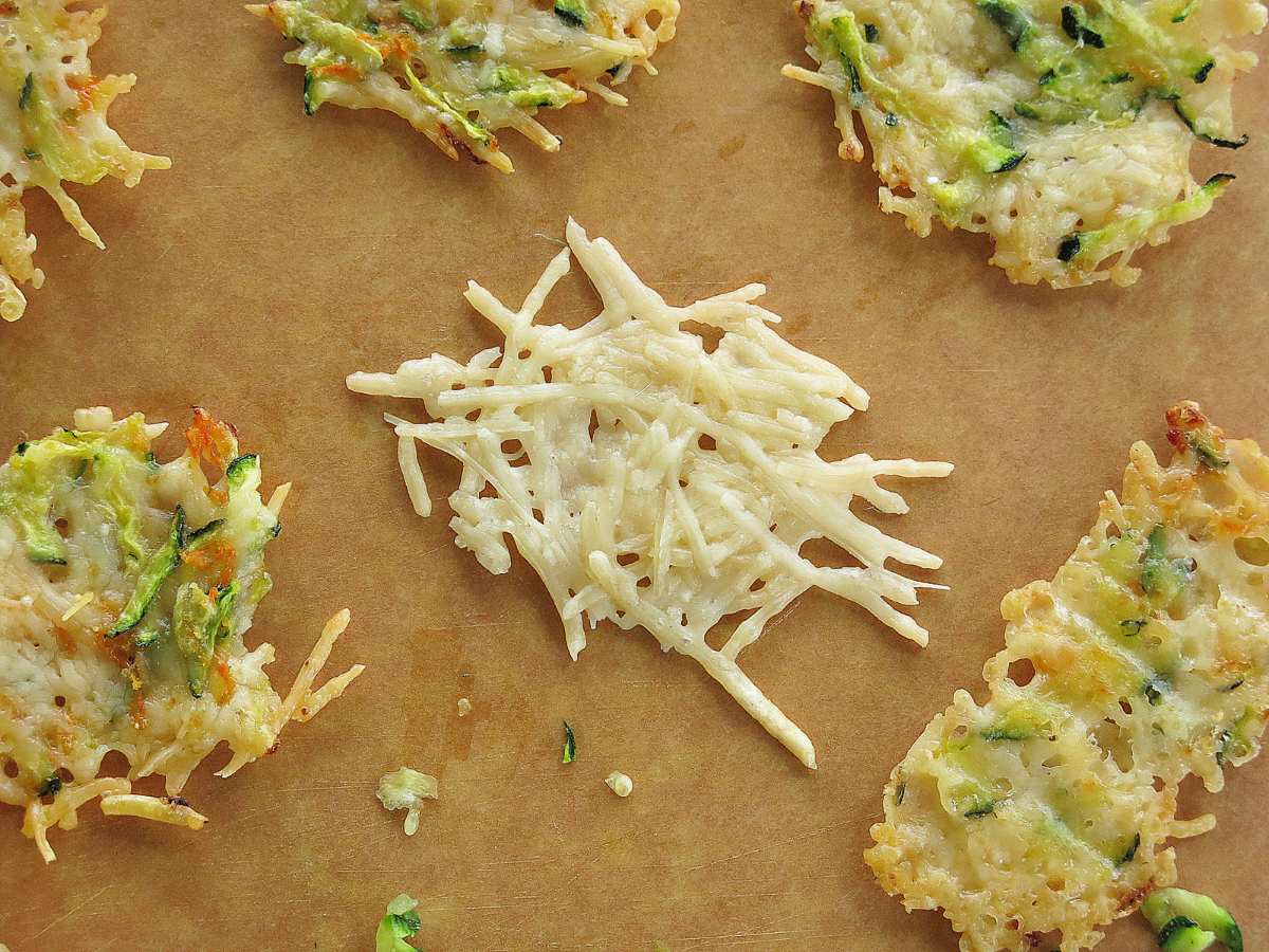 Keto Parmesan Cheese Crisp made with only Parmesan cheese in the center of a cutting board. The other crisps are made with vegetables.